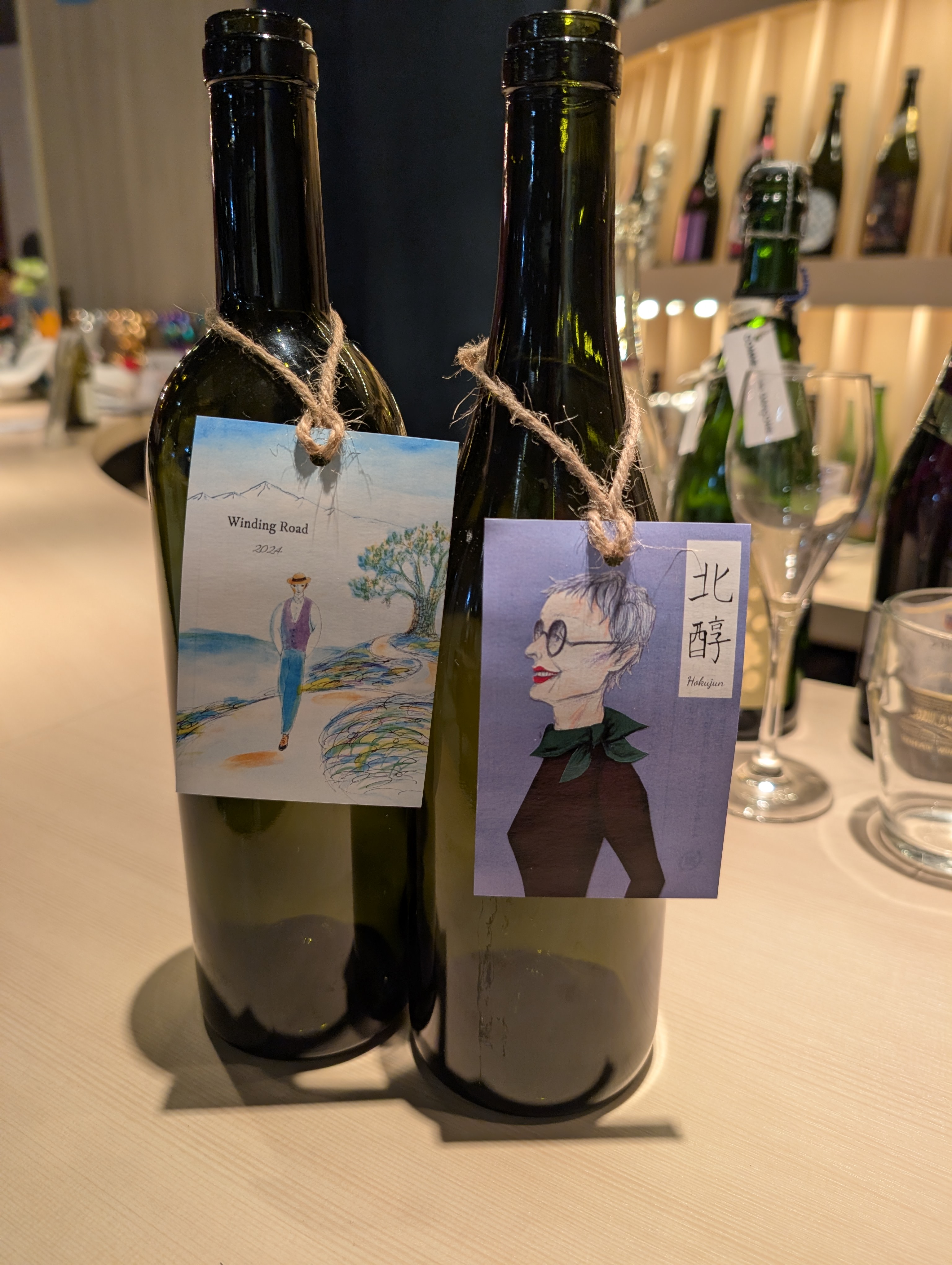 TSURUOKA TASTING COUNTERのカウンターに並ぶ、イラストの下げ札がついたワインボトル