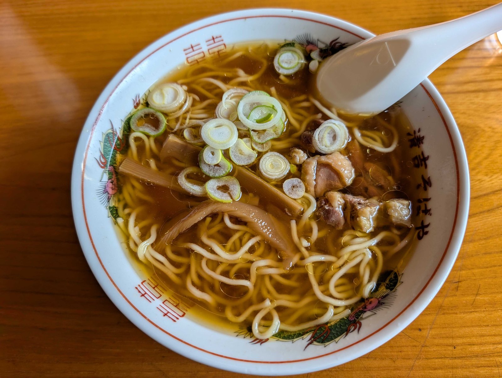 澄んだ醤油のつゆに細い麺。丼は赤い龍の絵に店名が入っている